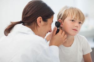 Female doctor looking in young patient's ear