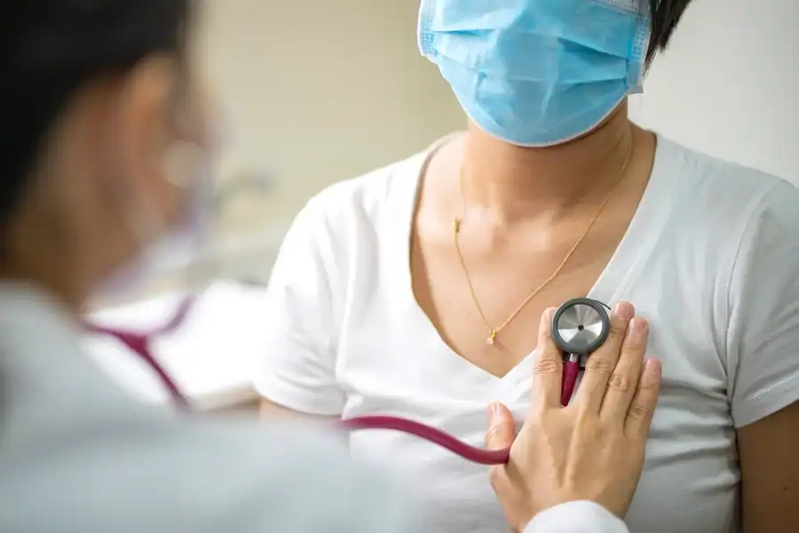 A close-up photo of a doctor using a stethoscope to listen for signs of pneumonia in a patient’s lungs.