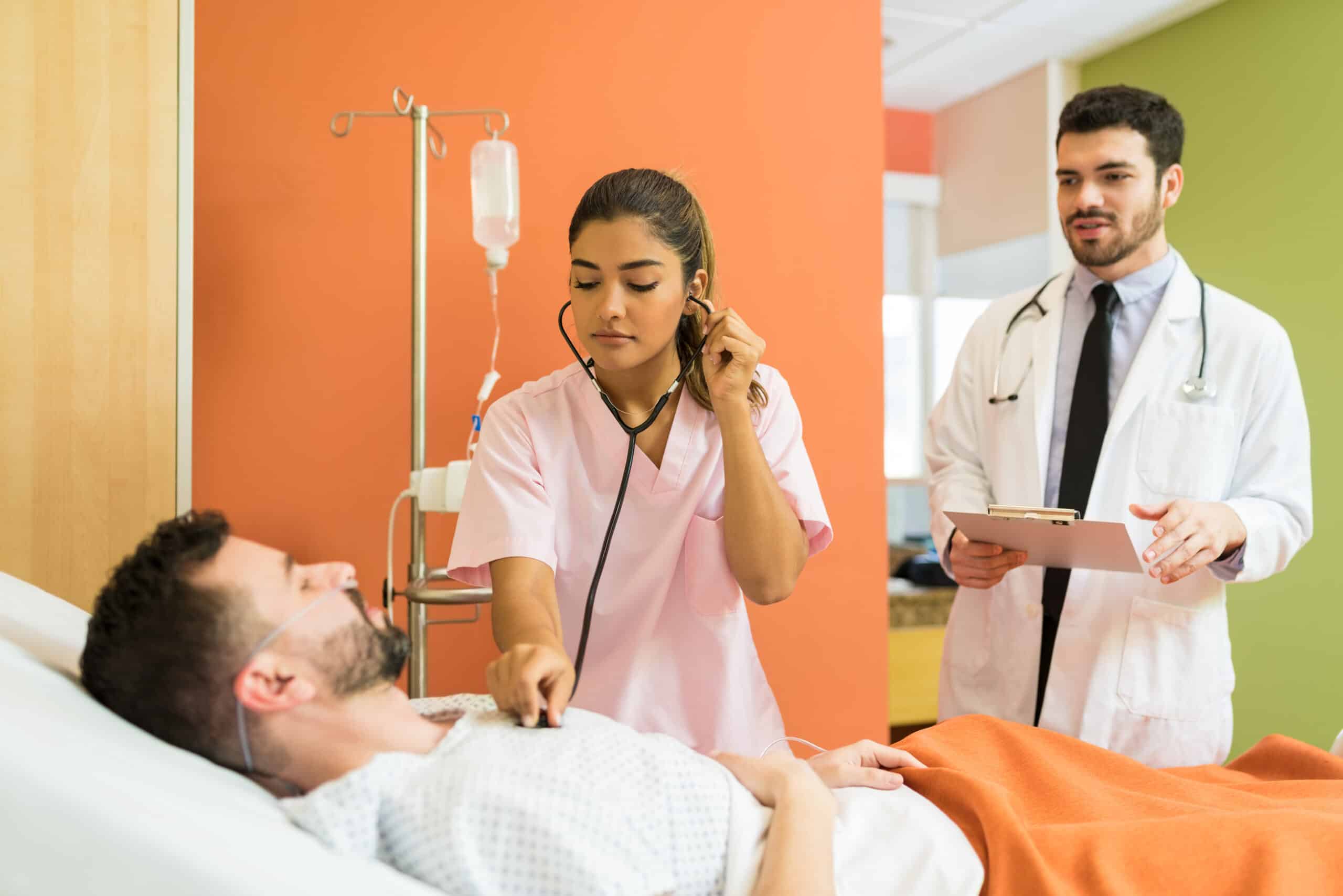 female doctor examining sick patient with stethoscope while male doctor analyzing reports hospital scaled