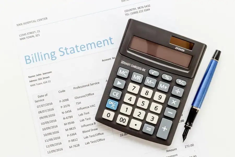 A calculator and pen on top of a medical bill.